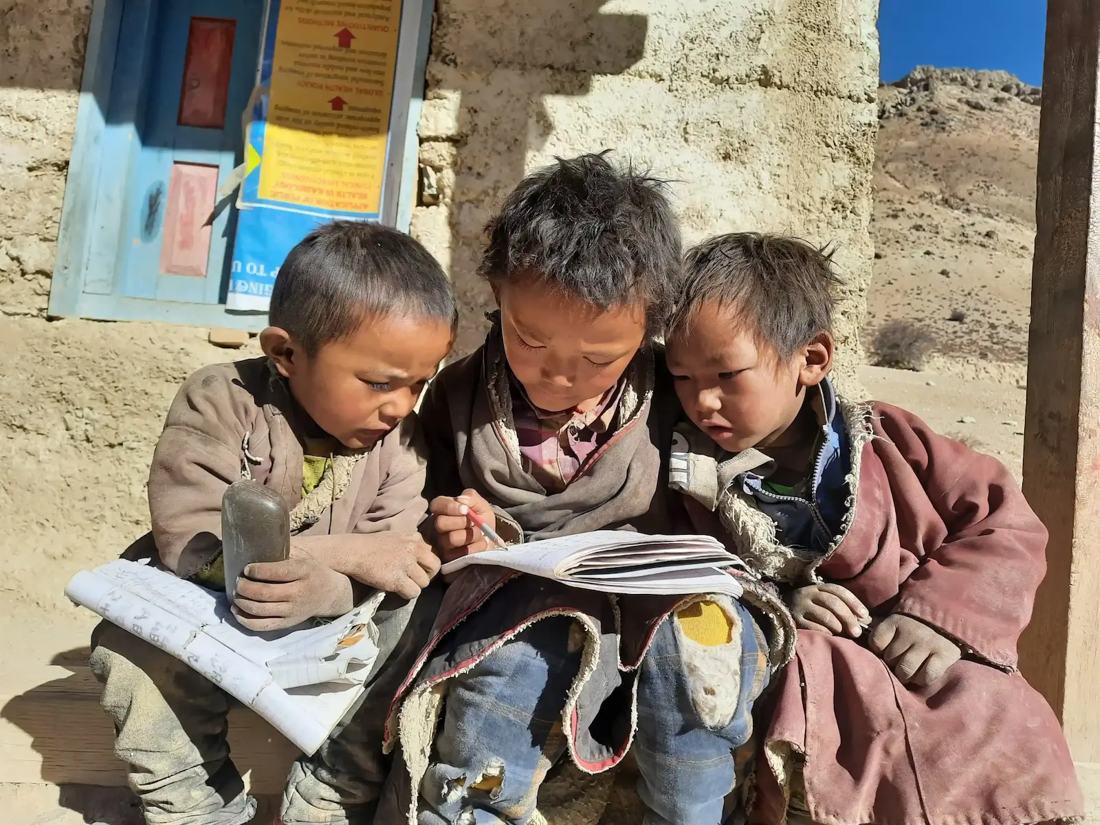 three children's reading together with a single book.